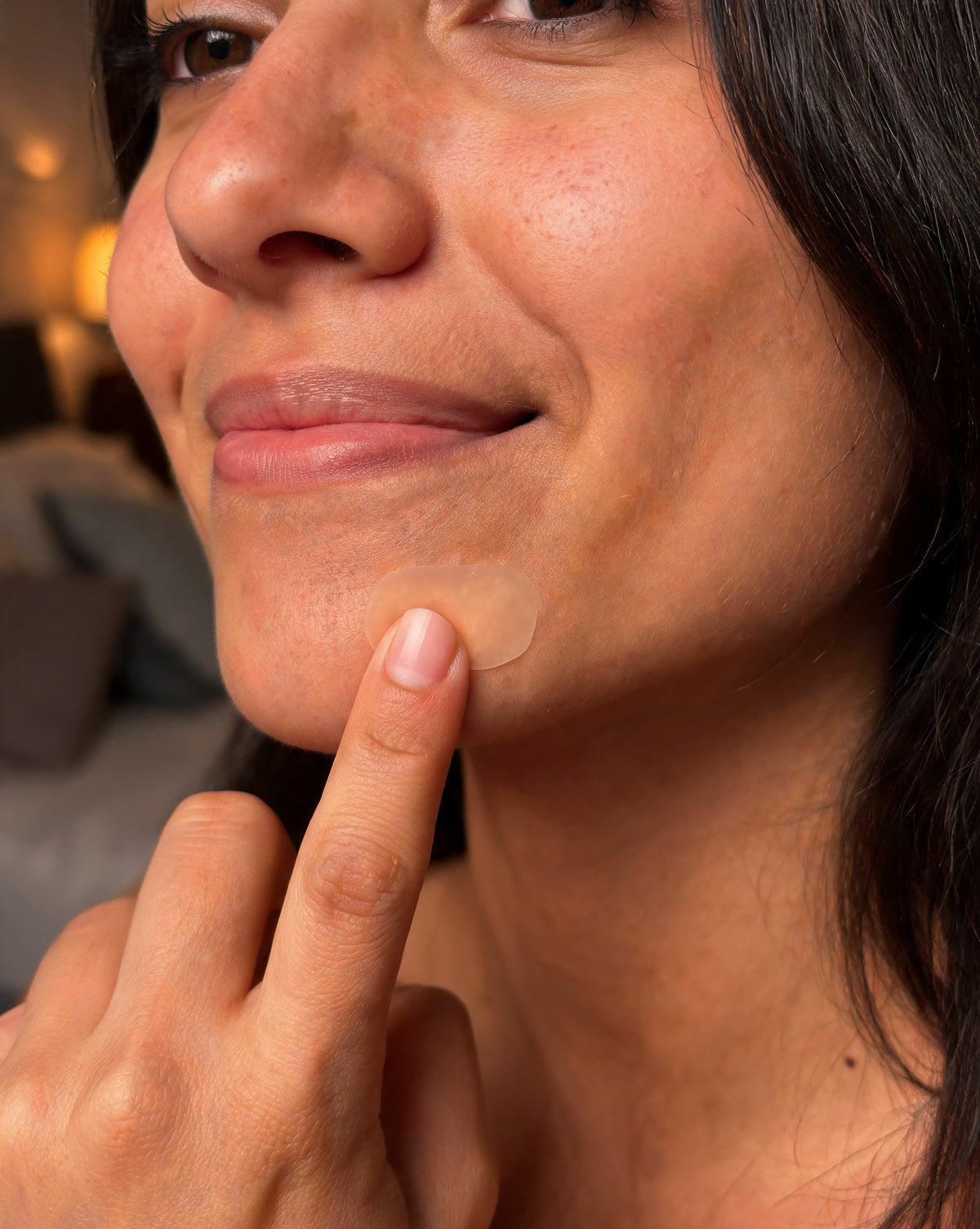 Woman smoothing a custom-cut hydrocolloid patch on her chin