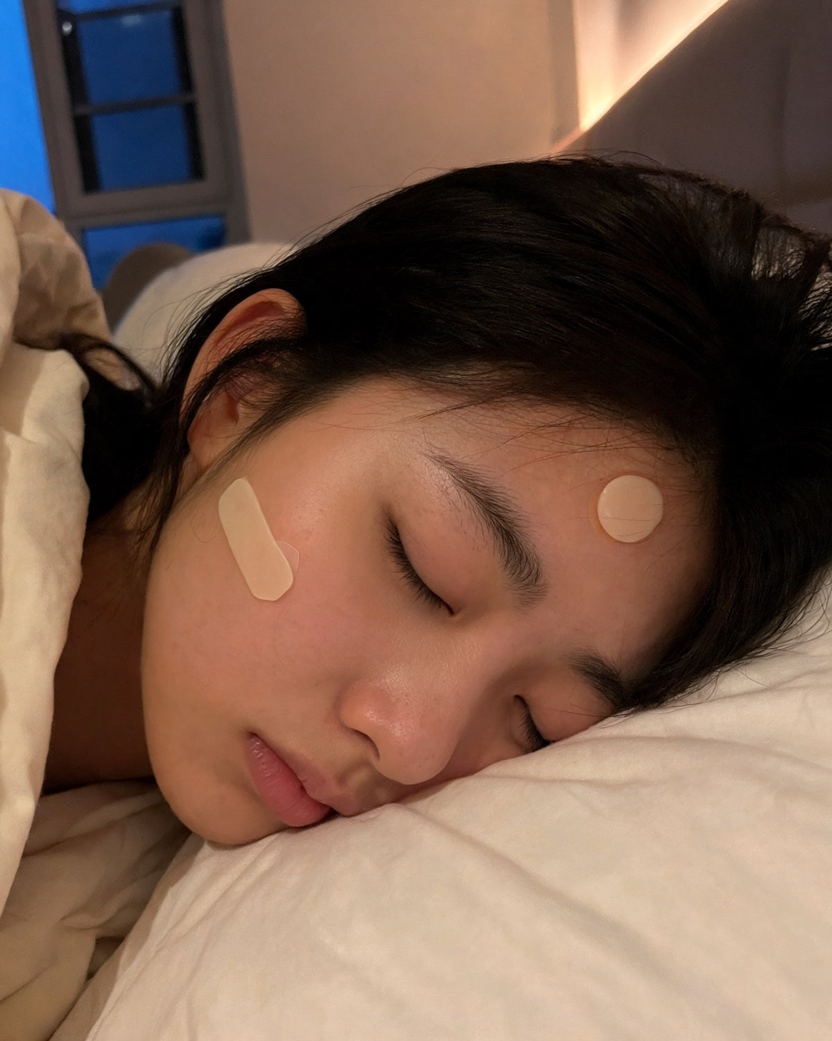 Woman asleep wearing a cut strip and a round patch overnight