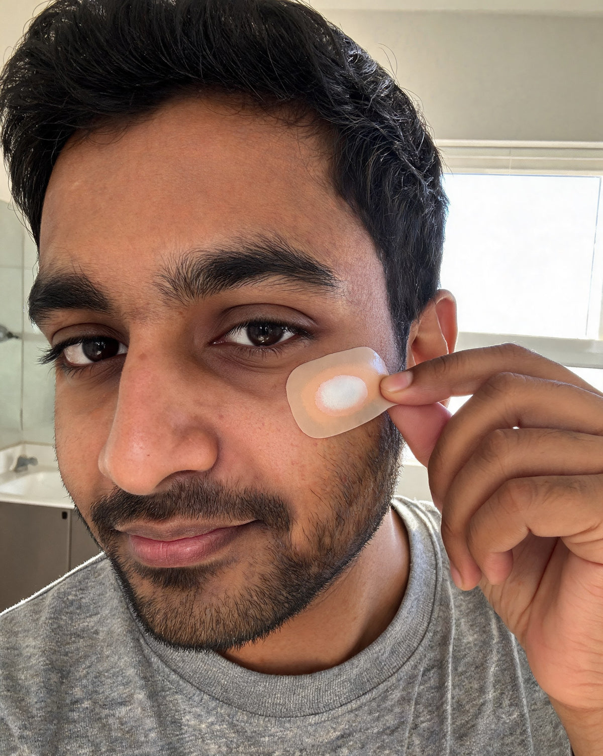 Man peeling off a patch in the morning, turned white where it absorbed fluid